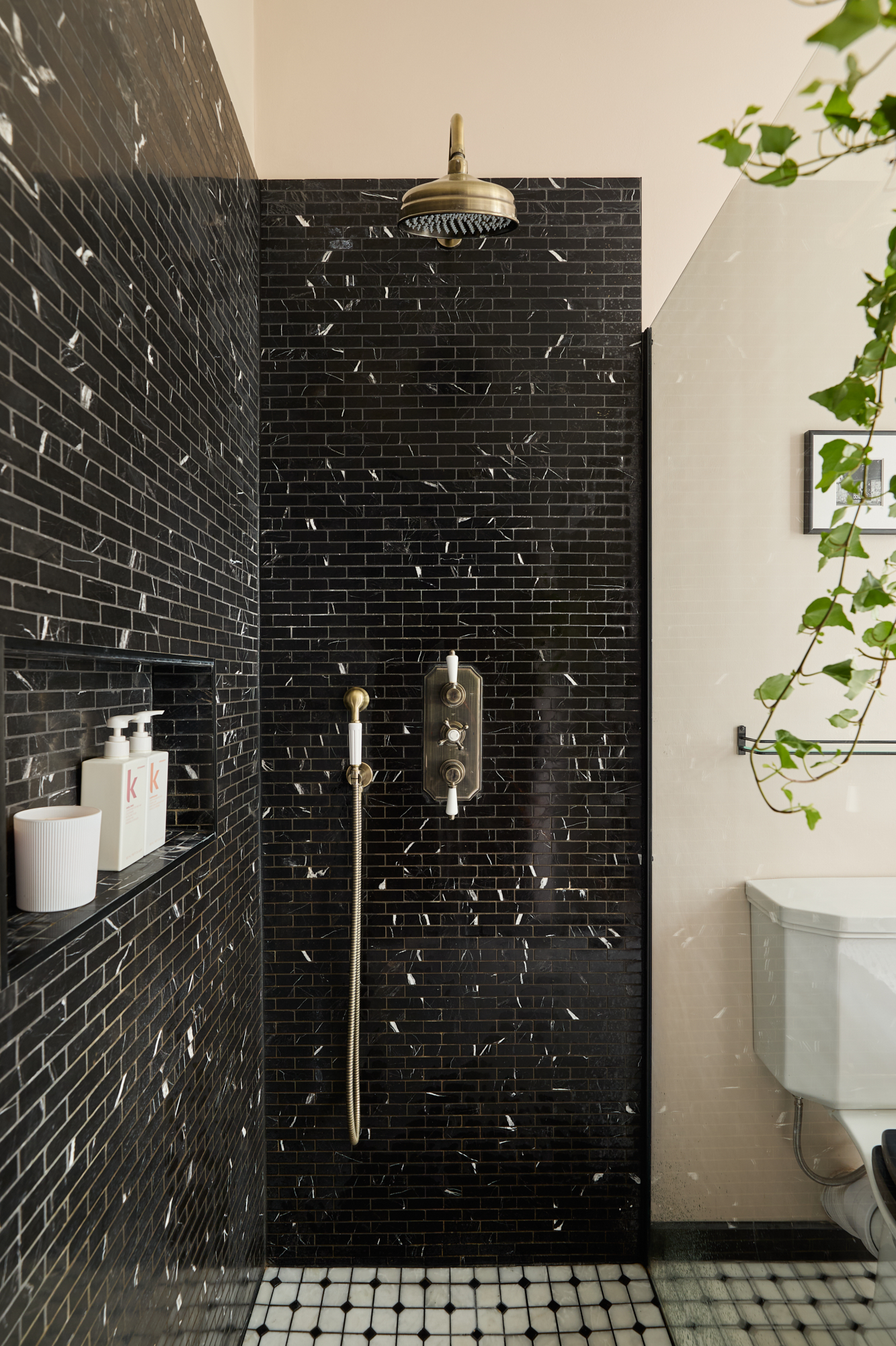 This striking shower room blends bold heritage finishes with a modern layout. Glossy black marble subway tiles and unlacquered vintage brass fittings elevate the everyday ritual of bathing into something exceptional.