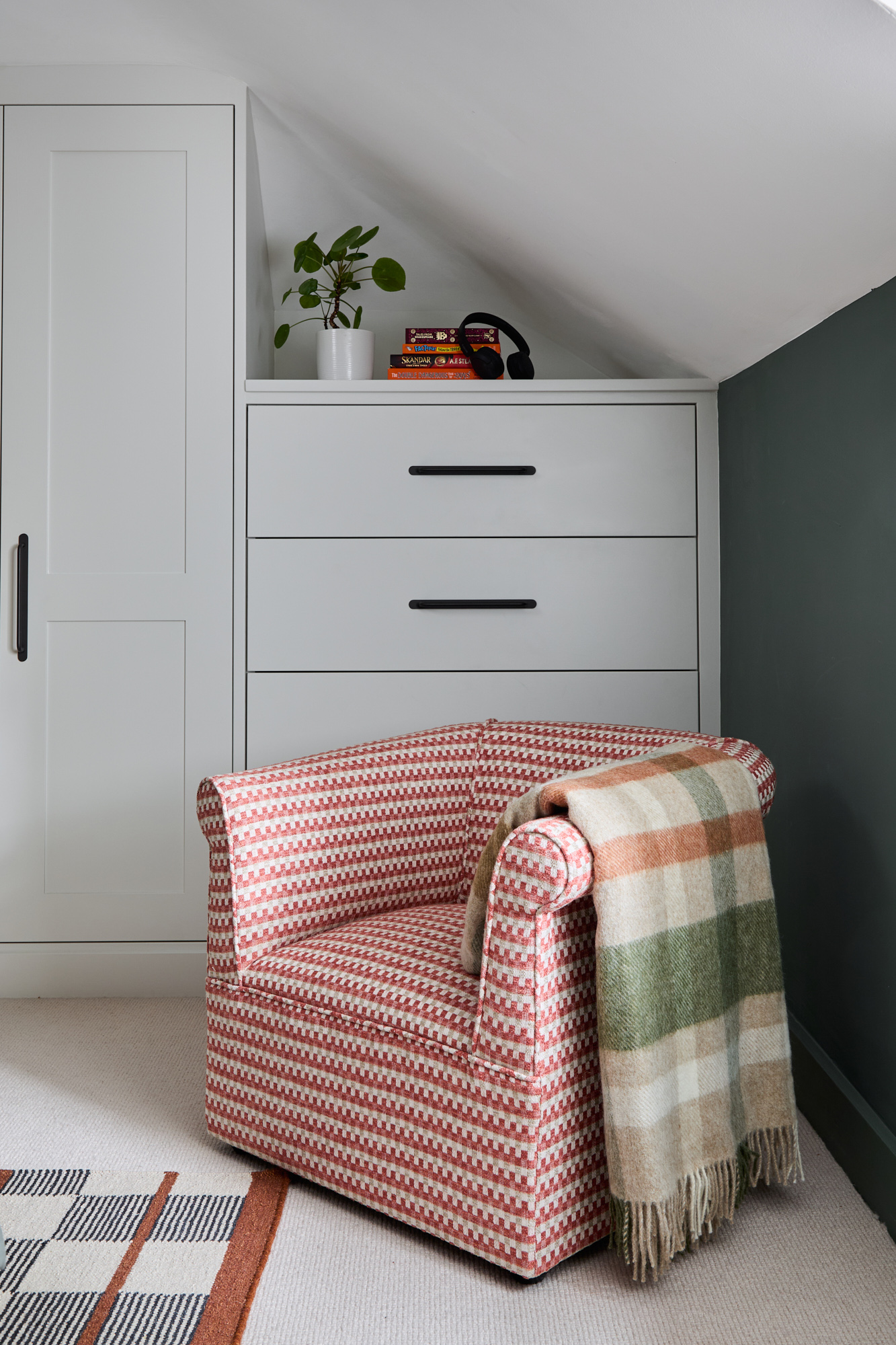 Cosy reading corner with vintage armchair, eco-friendly blanket, and bespoke joinery in a London period home.