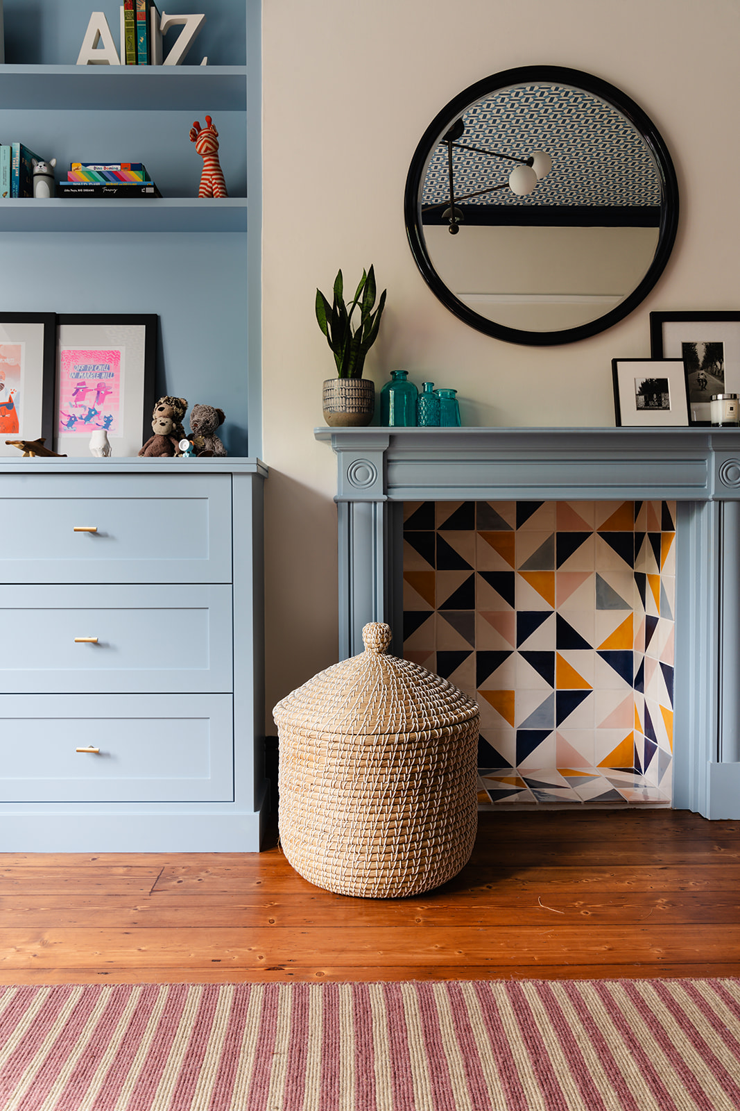 Blue joinery and patterned fireplace with woven basket, illustrating London interior design blending bespoke and high-street décor.