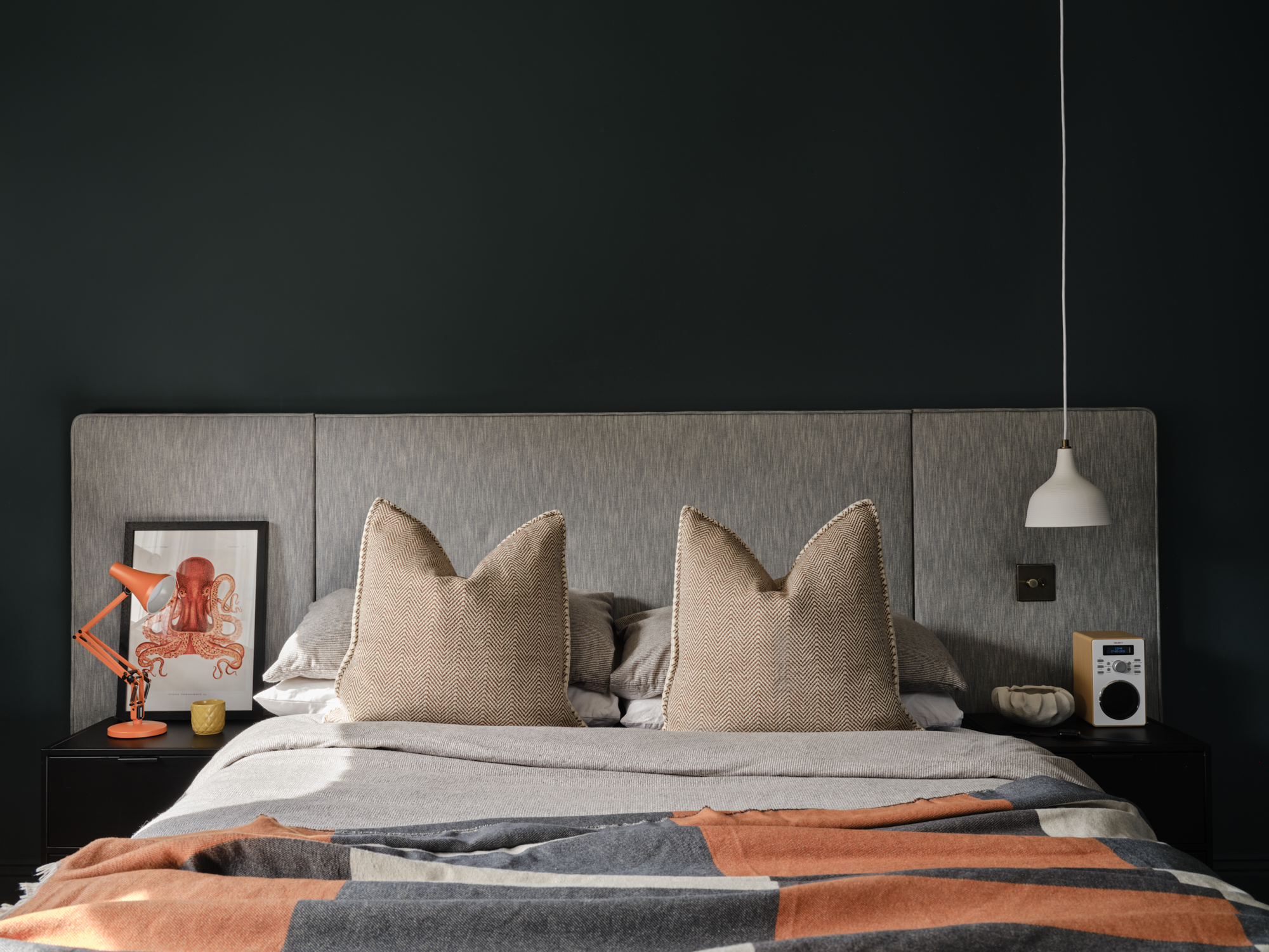 Dark teal teenage bedroom full bed view with orange Anglepoise and white pendant on either side, colourblock throw, London