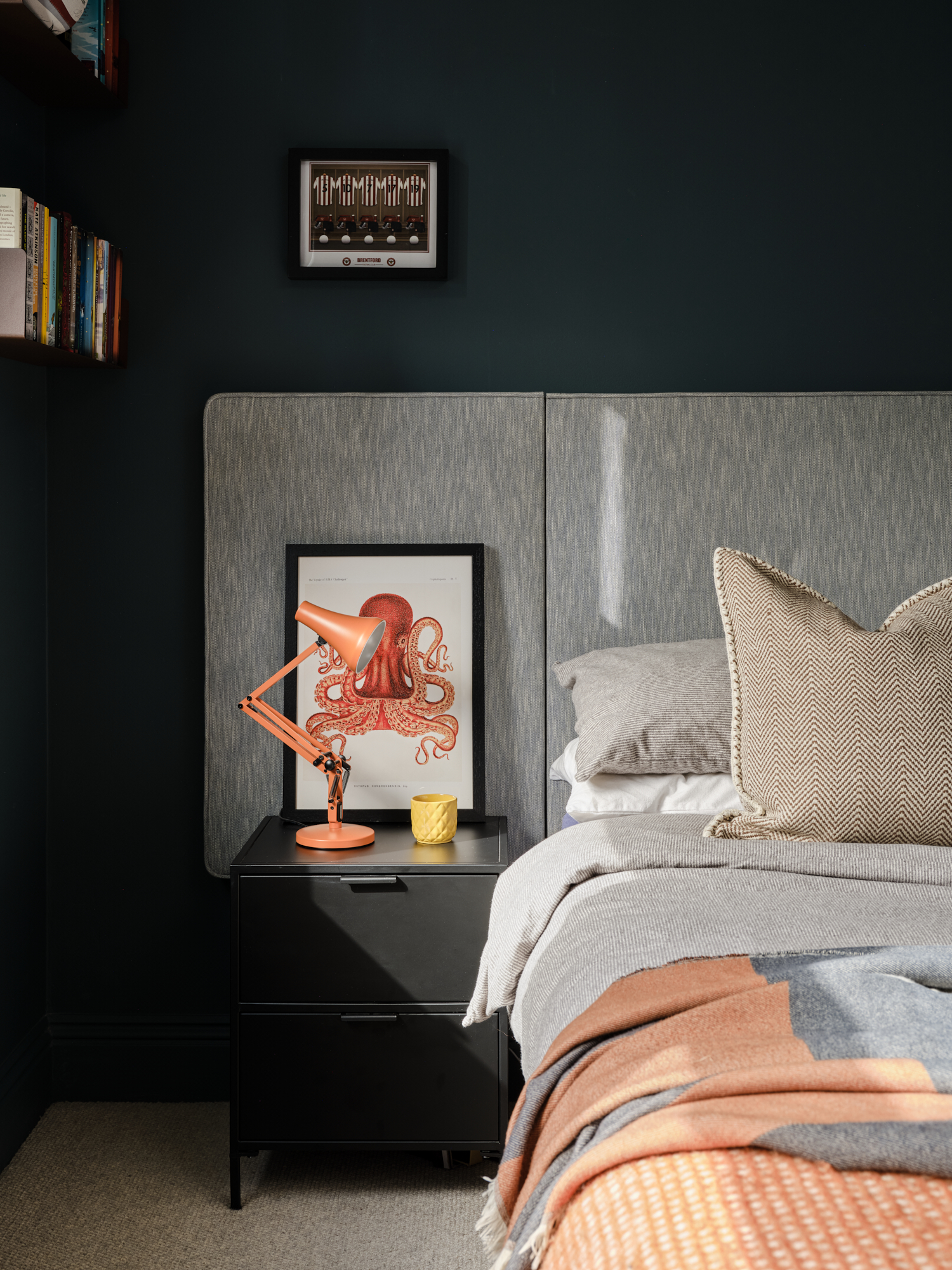 Teenage bedroom bedside with orange Anglepoise lamp and framed octopus print on dark teal wall, interior design St Margarets London