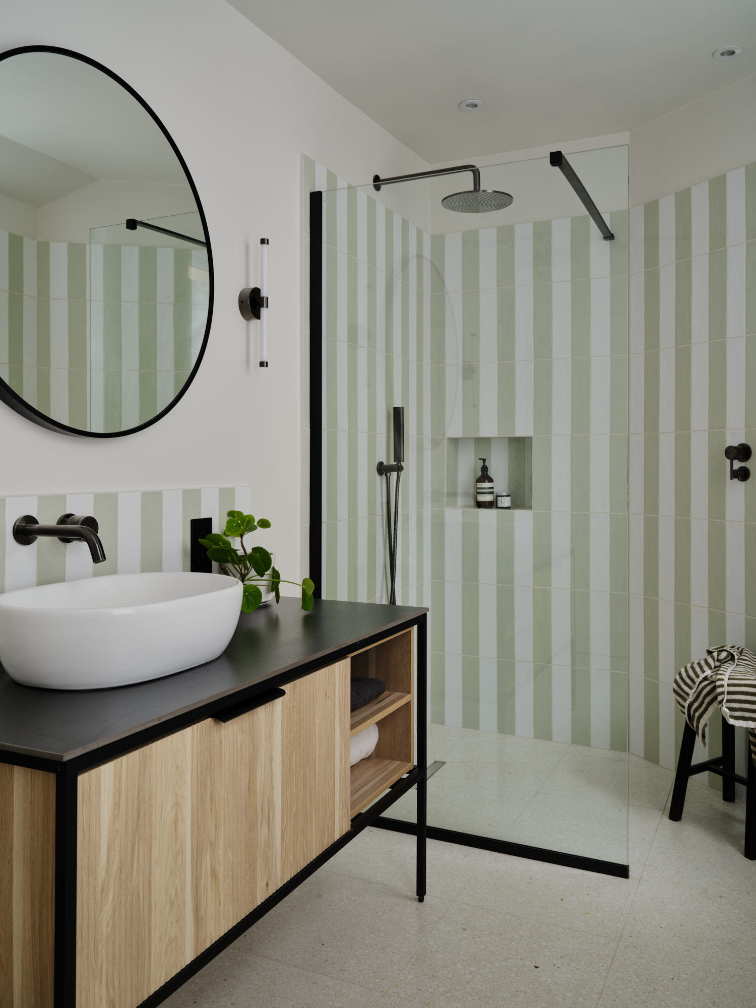 Sage stripe tile bathroom with vessel sink on open oak vanity, pilea plant and walk-in shower, interior design St Margarets London